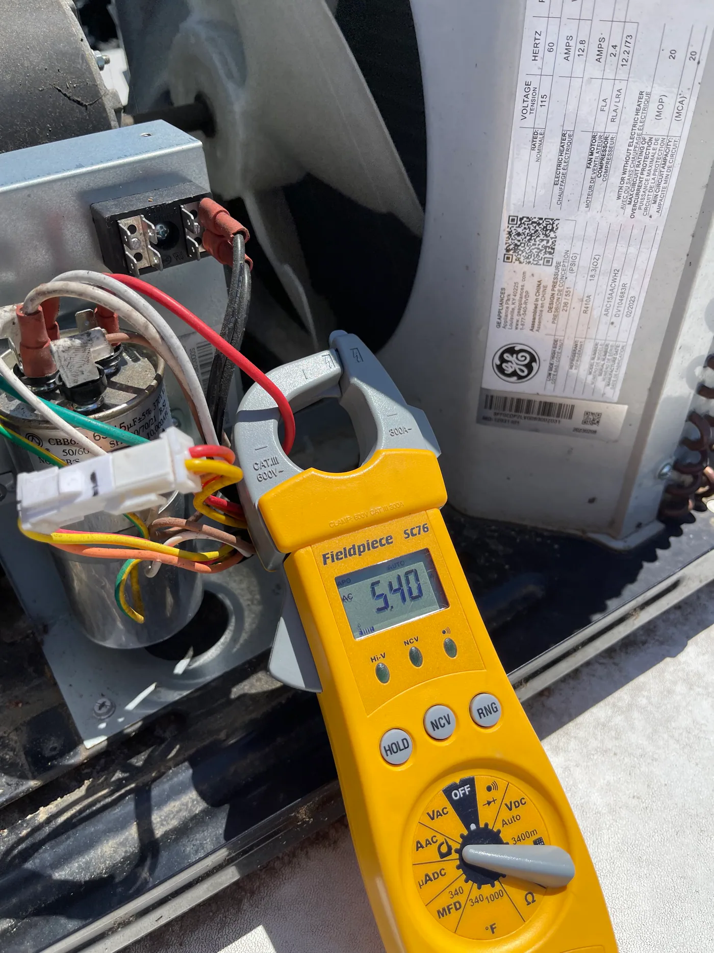 HVAC technician measuring current inside a GE rooftop RV air conditioner
