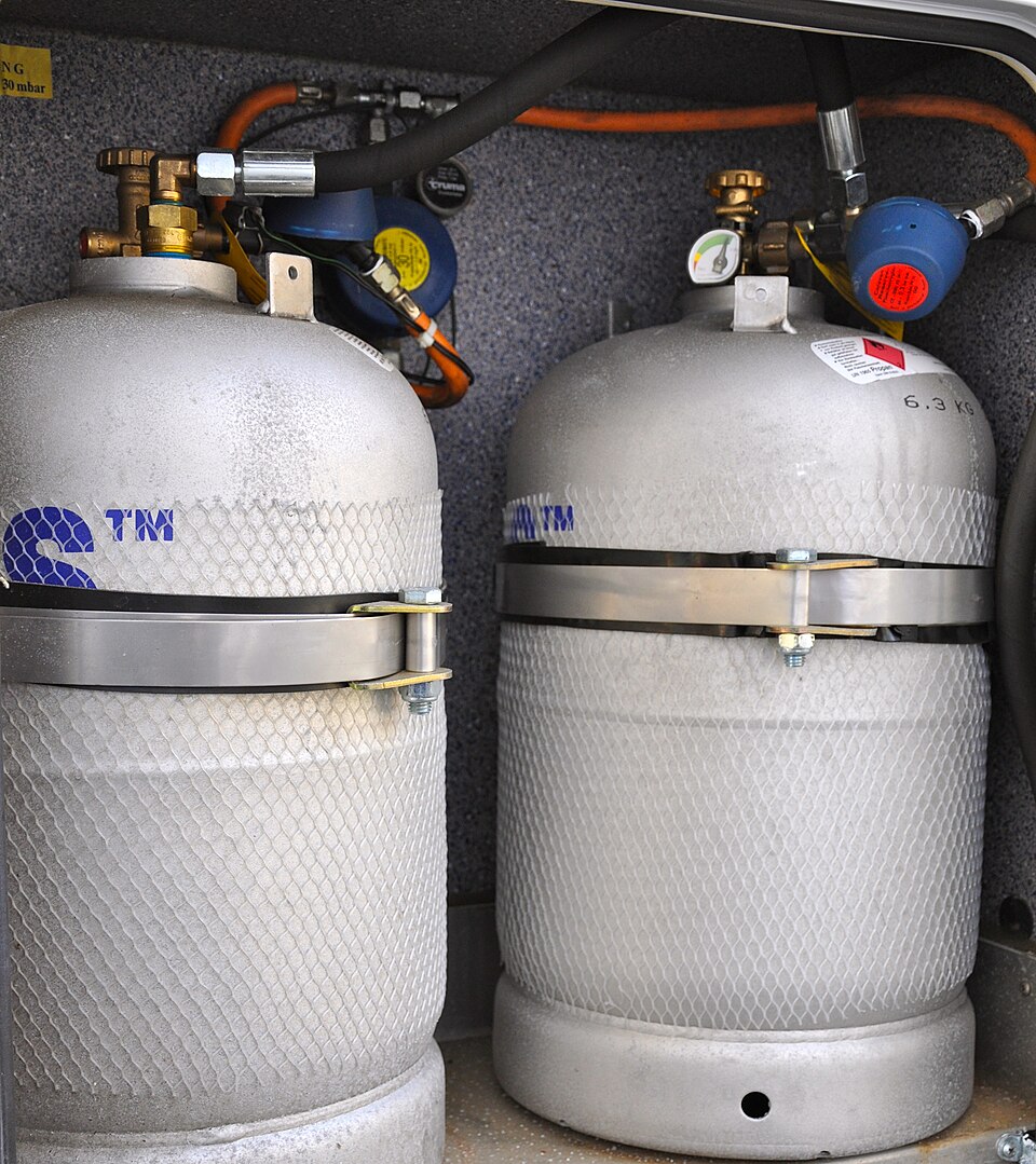 Two LPG cylinders held by metal retaining bands inside a camper gas compartment